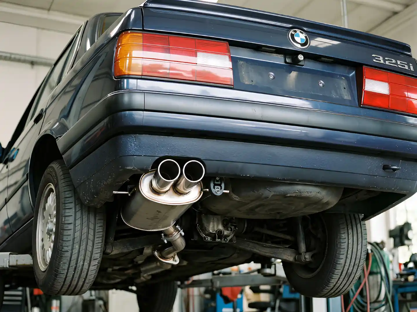 Classic BMW on a lift with its exhaust pipes and muffler exposed