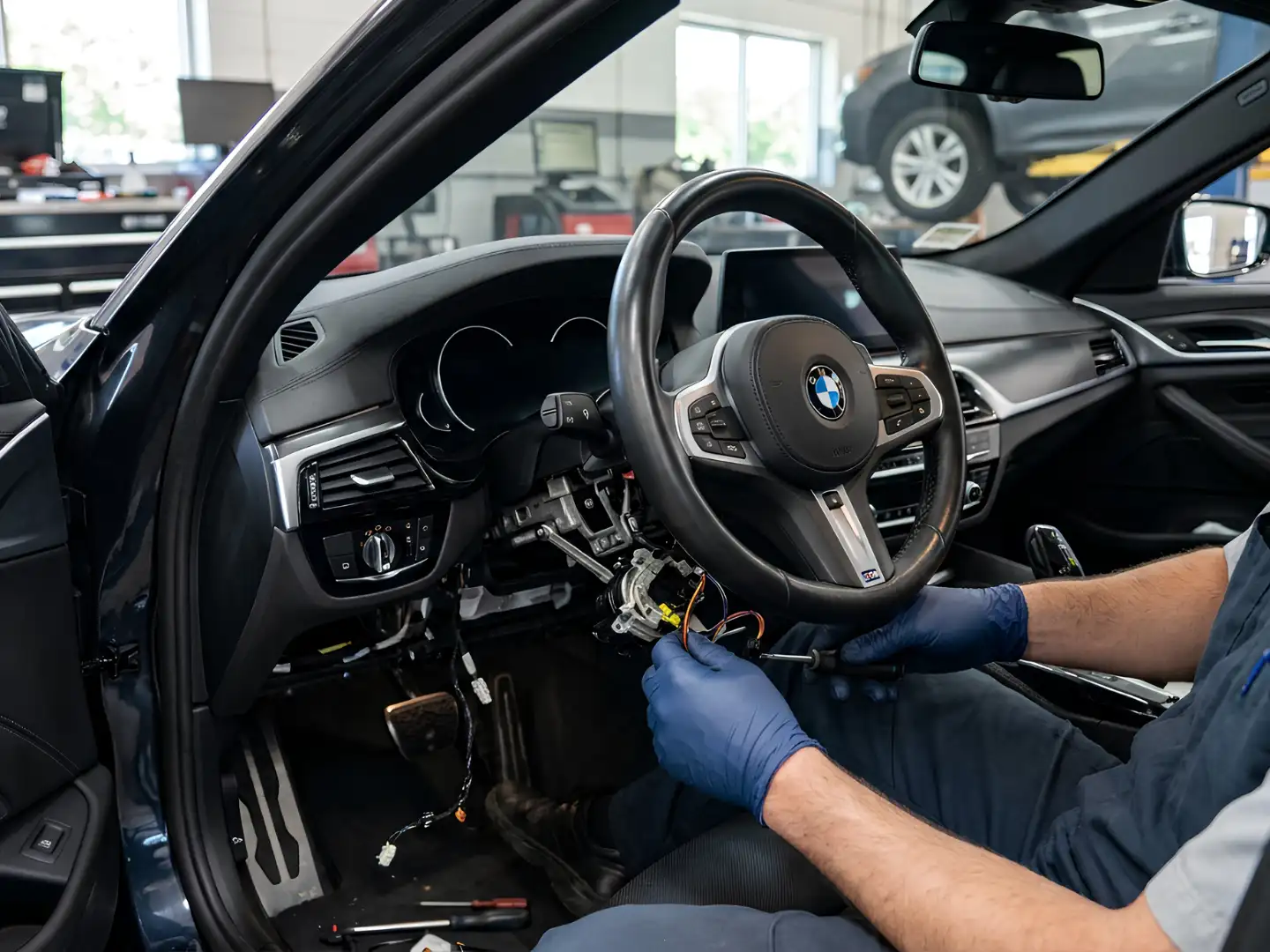 Technician working behind a BMW steering wheel on the steering column