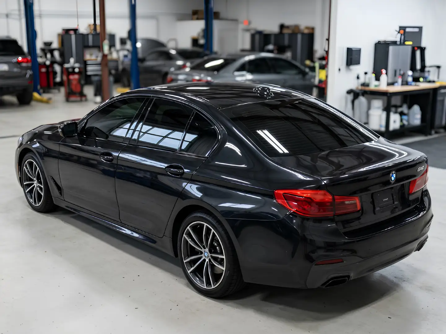 Black BMW sedan with freshly tinted windows in a workshop